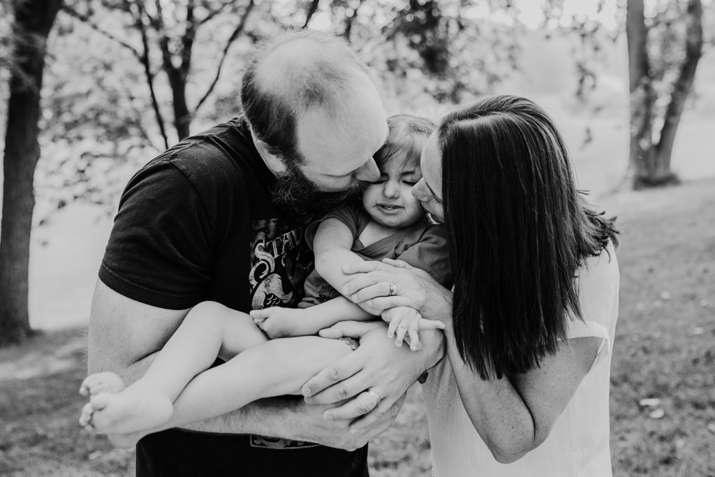 parents holding and kissing child